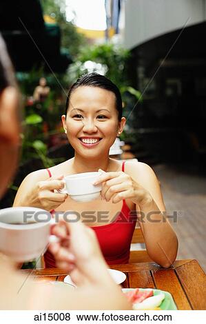 Stock Photo - Woman holding cup, smiling, over the shoulder view. Fotosearch