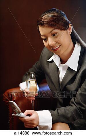 Woman holding glass of champagne and mobile phone, text messaging View Large Photo Image Stock Photo - Woman holding glass of champagne and mobile phone, text messaging. Fotosearch