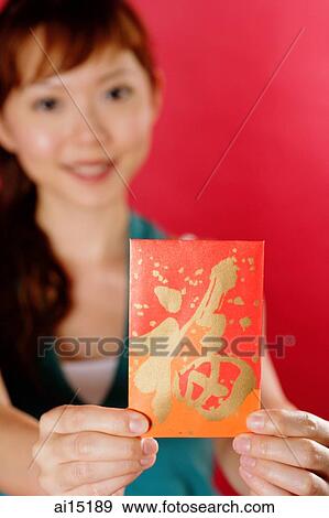 Woman holding red packet towards camera View Large Photo Image Stock Photo - Woman holding red packet towards camera. Fotosearch