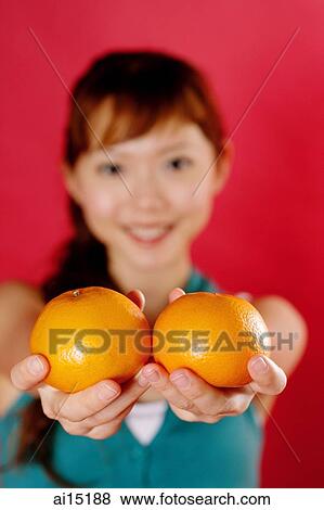 Woman holding two oranges towards camera View Large Photo Image Stock Photo - Woman holding two oranges towards camera. Fotosearch