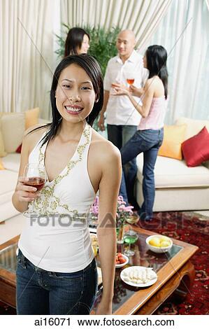 Woman holding wine glass, looking at camera, people in the background View Large Photo Image Stock Image - Woman holding wine glass, looking at camera, people in the background. Fotosearch