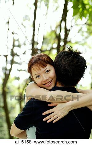 Stock Photo - Woman hugging man, facing camera. Fotosearch
