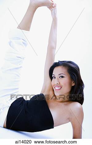 Stock Image - Woman in black tube top, stretching, touching foot. Fotosearch