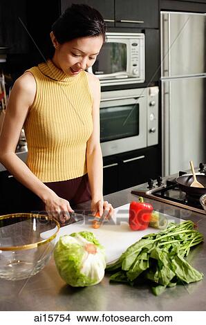 Picture - Woman in kitchen, cutting vegetables. Fotosearch