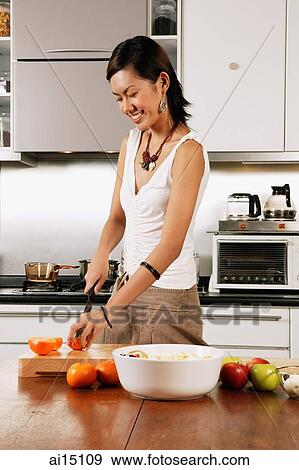 Stock Photo - Woman in kitchen, cutting vegetables. Fotosearch