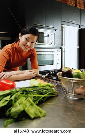 Woman in kitchen, leaning on kitchen counter, looking at camera View Large Photo Image Stock Image - Woman in kitchen, leaning on kitchen counter, looking at camera. Fotosearch