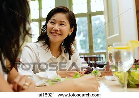 Woman in restaurant smiling at person next to her View Large Photo Image Stock Image - Woman in restaurant smiling at person next to her. Fotosearch