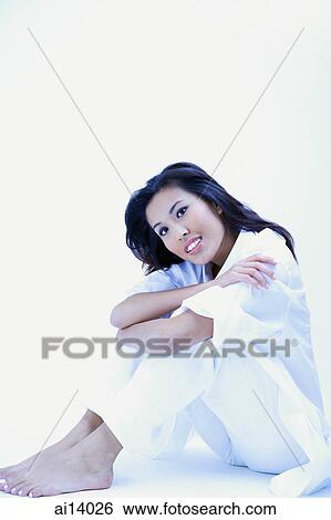 Woman in white shirt and pants, hugging knees, looking at camera View Large Photo Image Stock Photograph - Woman in white shirt and pants, hugging knees, looking at camera. Fotosearch
