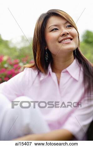 Stock Photo - Woman looking at away, hugging knee, portrait. Fotosearch