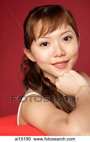 Stock Image - Woman looking at camera, hand on chin. Fotosearch