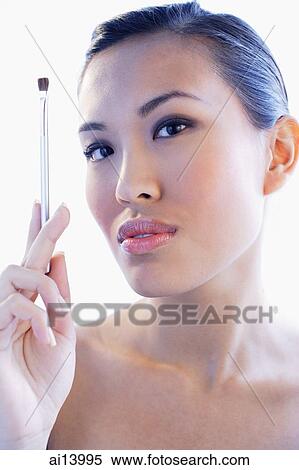 Woman looking at camera, holding make-up brush View Large Photo Image Stock Photography - Woman looking at camera, holding make-up brush. Fotosearch