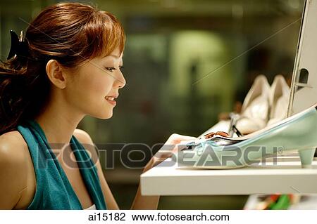 Stock Image - Woman looking at shoes in shoe store. Fotosearch