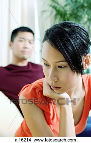 Woman looking away, hand on chin, man in the background View Large Photo Image Picture - Woman looking away, hand on chin, man in the background. Fotosearch