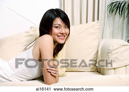 Woman lying on sofa, looking at camera View Large Photo Image Stock Image - Woman lying on sofa, looking at camera. Fotosearch