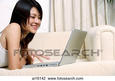 Woman lying on sofa, using laptop View Large Photo Image Stock Image - Woman lying on sofa, using laptop. Fotosearch