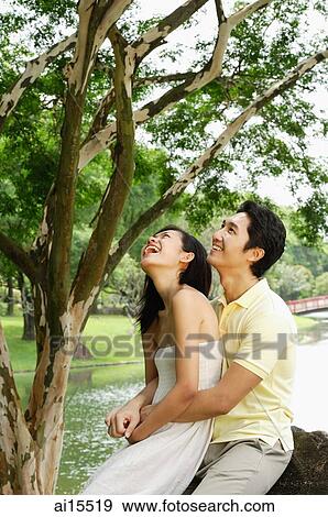 Woman sitting on mans lap, man embracing her, both looking up View Large Photo Image Stock Photo - Woman sitting on mans lap, man embracing her, both looking up. Fotosearch