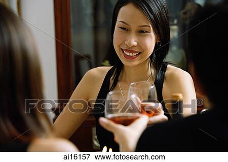 Woman smiling, holding wine glass, toasting with person sitting opposite View Large Photo Image Stock Photo - Woman smiling, holding wine glass, toasting with person sitting opposite. Fotosearch