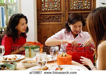 Woman unwrapping gifts with friends View Large Photo Image Stock Photo - Woman unwrapping gifts with friends. Fotosearch