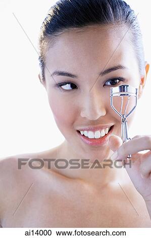 Stock Image - Woman using eyelash curler. Fotosearch
