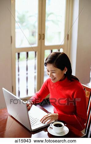 Woman using laptop, cup and saucer on table next to her View Large Photo Image Stock Image - Woman using laptop, cup and saucer on table next to her. Fotosearch