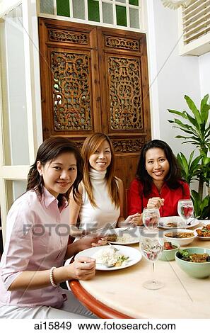 Stock Photo - Women having a meal at restaurant, looking at camera. Fotosearch