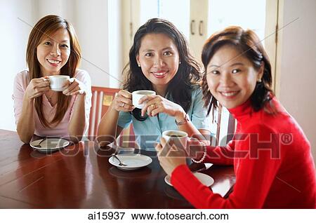 Women in cafe holding cups, smiling at camera View Large Photo Image Stock Photo - Women in cafe holding cups, smiling at camera. Fotosearch