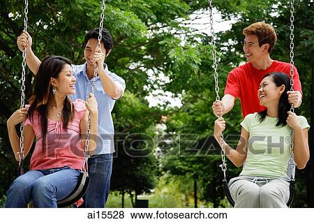 Women on swings, men standing behind them View Large Photo Image Stock Photo - Women on swings, men standing behind them. Fotosearch