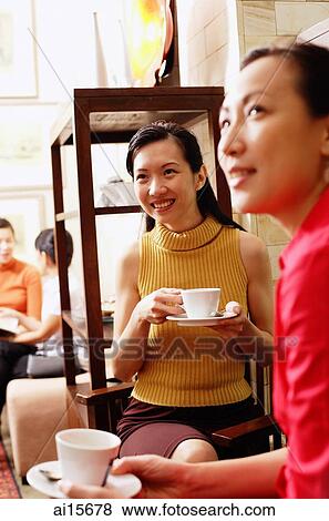 Women sitting, holding cups and saucers, looking away View Large Photo Image Stock Photo - Women sitting, holding cups and saucers, looking away. Fotosearch