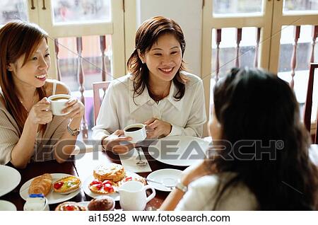 Stock Photo - Women sitting in cafe, having tea. Fotosearch
