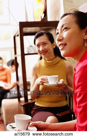 Women sitting with cups and saucers, looking away View Large Photo Image Stock Photo - Women sitting with cups and saucers, looking away. Fotosearch