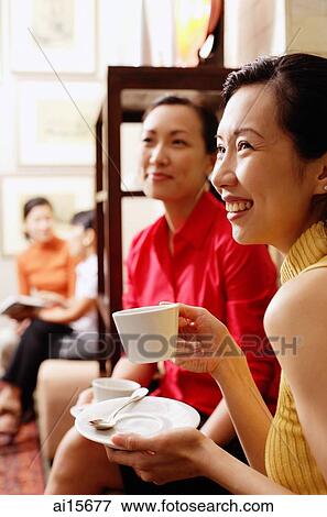 Women smiling, holding cups and saucers, looking away View Large Photo Image Stock Photo - Women smiling, holding cups and saucers, looking away. Fotosearch