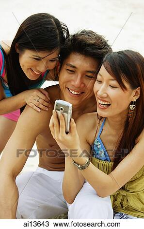 Stock Image - Young adults looking at mobile phone. Fotosearch