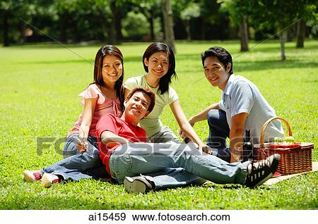 Young adults sitting in park, looking at camera View Large Photo Image Stock Photo - Young adults sitting in park, looking at camera. Fotosearch