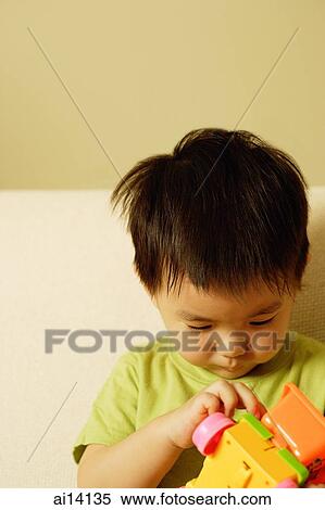 Young boy looking at toy View Large Photo Image Stock Photography - Young boy looking at toy. Fotosearch