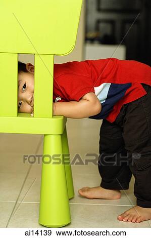 Young boy peeking behind chair, looking at camera View Large Photo Image Stock Photo - Young boy peeking behind chair, looking at camera. Fotosearch