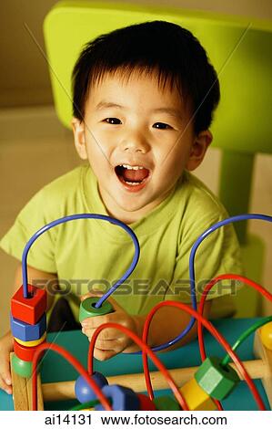 Young boy playing with toy, looking at camera View Large Photo Image Stock Image - Young boy playing with toy, looking at camera. Fotosearch
