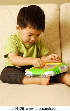 Young boy with toy on sofa View Large Photo Image Stock Photograph - Young boy with toy on sofa. Fotosearch