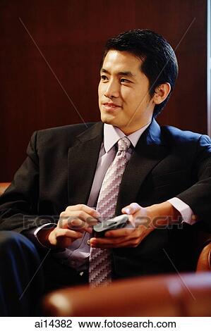 Young businessman holding PDA, looking away View Large Photo Image Stock Image - Young businessman holding PDA, looking away. Fotosearch
