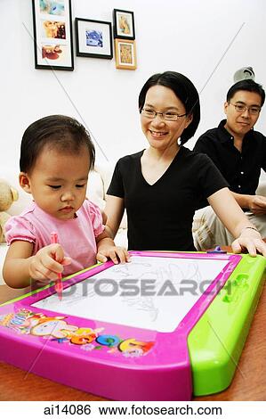 Young girl drawing on magnetic block, parents watching her View Large Photo Image Stock Photograph - Young girl drawing on magnetic block, parents watching her. Fotosearch