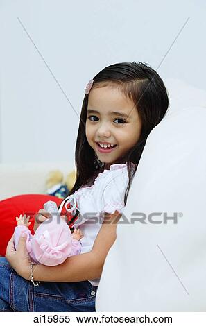 Young girl holding a doll, smiling at camera View Large Photo Image Stock Photography - Young girl holding a doll, smiling at camera. Fotosearch