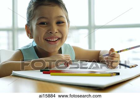 Picture - Young girl holding pencil, smiling at camera. Fotosearch