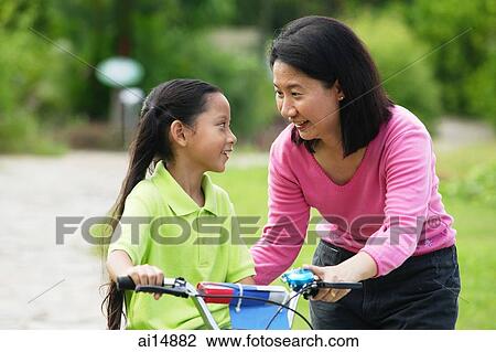 Young girl on bicycle, mother next to her, face to face View Large Photo Image Stock Image - Young girl on bicycle, mother next to her, face to face. Fotosearch