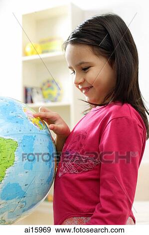 Young girl standing and looking at globe View Large Photo Image Stock Photo - Young girl standing and looking at globe. Fotosearch
