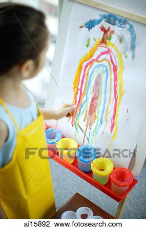 Young girl standing in front of rainbow painting on easel View Large Photo Image Stock Image - Young girl standing in front of rainbow painting on easel. Fotosearch