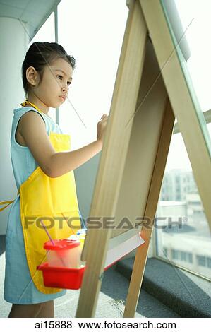 Young girl wearing apron, standing in front of easel, painting View Large Photo Image Stock Photo - Young girl wearing apron, standing in front of easel, painting. Fotosearch