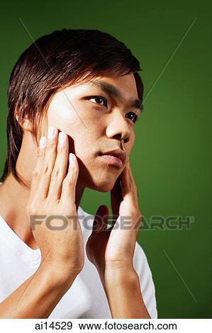 Young man applying aftershave, looking away View Large Photo Image Stock Photo - Young man applying aftershave, looking away. Fotosearch