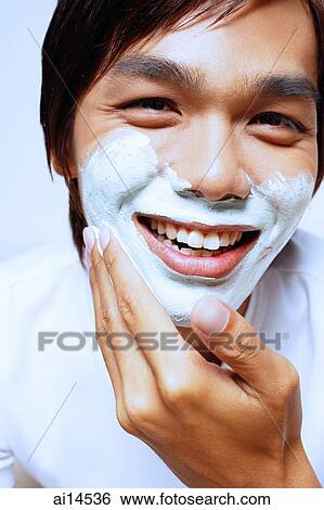 Young man applying shaving foam on face View Large Photo Image Stock Photograph - Young man applying shaving foam on face. Fotosearch
