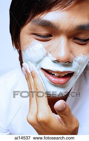Young man applying shaving foam on face, looking down View Large Photo Image Stock Photo - Young man applying shaving foam on face, looking down. Fotosearch