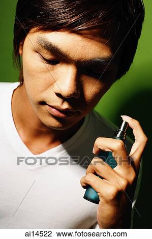 Young man holding bottle of perfume View Large Photo Image Stock Image - Young man holding bottle of perfume. Fotosearch