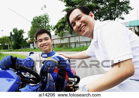 Young man in go-cart, father crouching down next to him, both looking at camera View Large Photo Image Stock Photograph - Young man in go-cart, father crouching down next to him, both looking at camera. Fotosearch